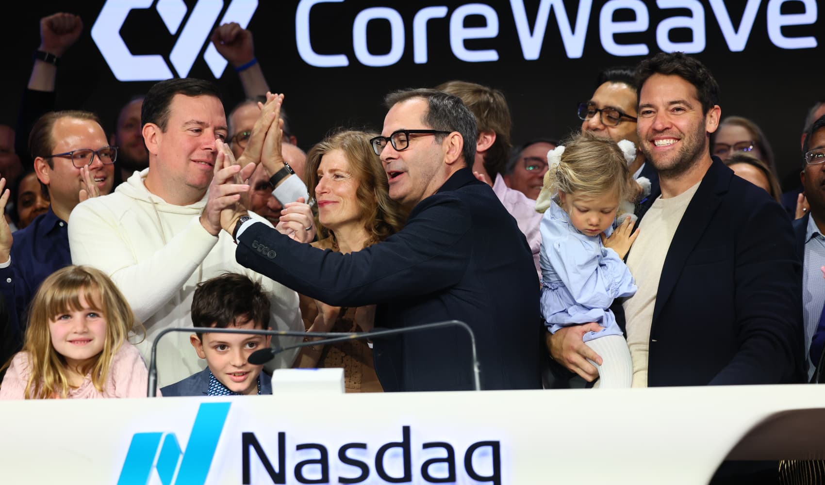 CoreWeave founders Brian Venturo, at left in sweatshirt, and Mike Intrator slap five after ringing the opening bell at Nasdaq headquarters in New York on March 28, 2025.